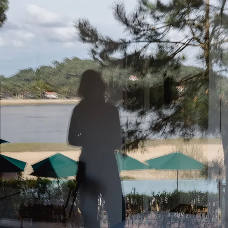 Feminine shadow behind the bay window of the balcony in the superior lake-view room at Les Hortensias du Lac in Hossegor.